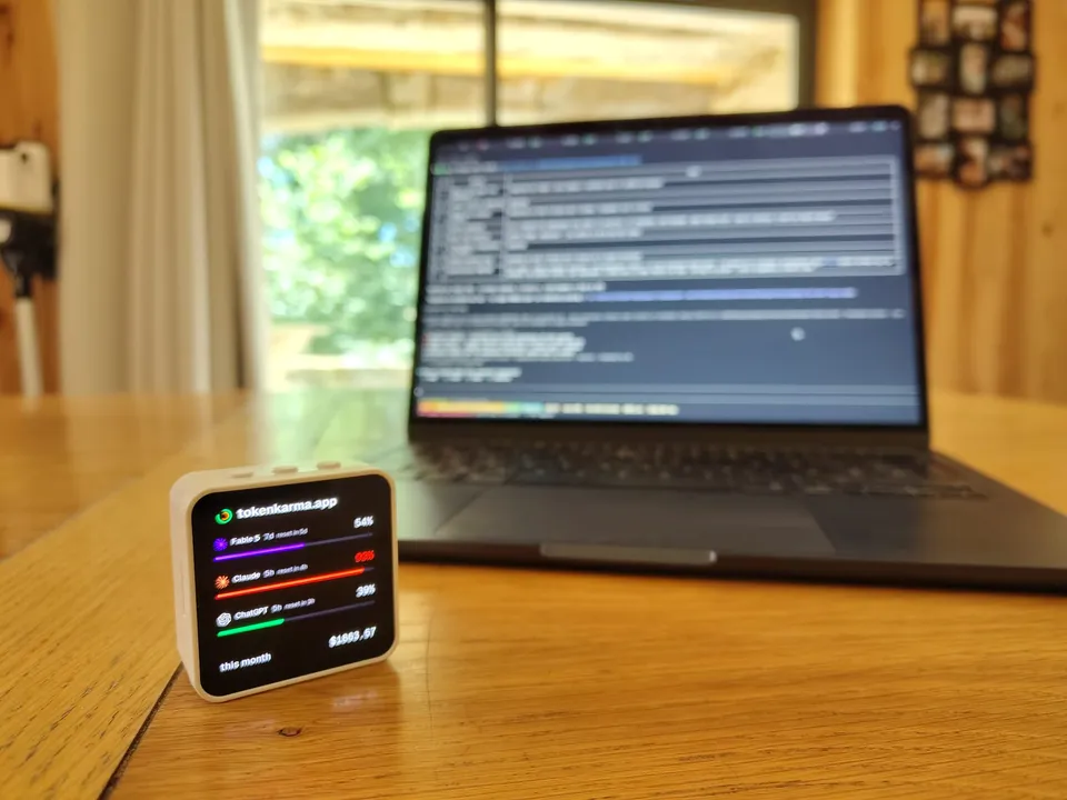 Toky on a desk next to a keyboard, MacBook with a terminal session open behind it